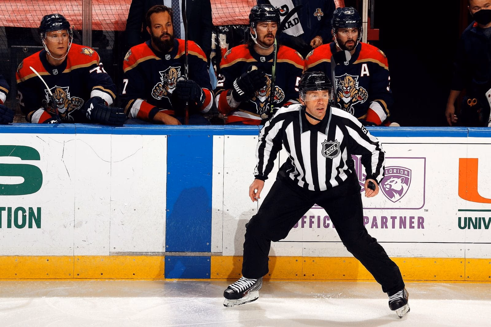 Un juge de lignes de la NHL en maillot rayé noir et blanc, sur la glace, devant le banc des joueurs des Panthers de la Floride