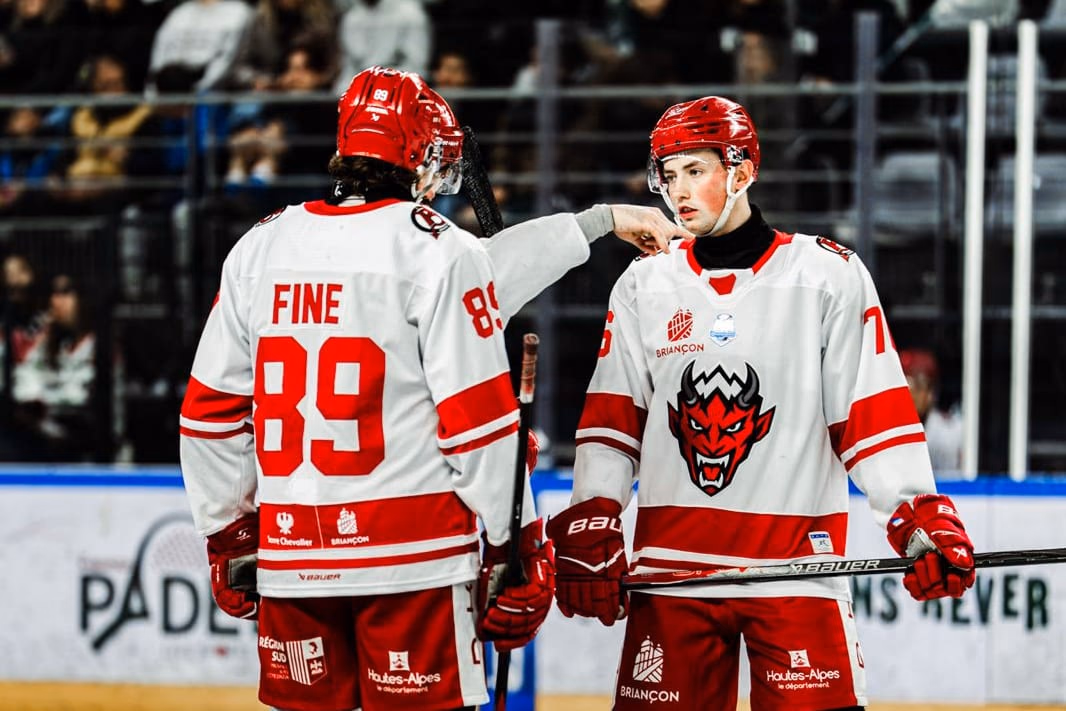 Antonin Fine, n° 89 des Diables Rouges, de dos, et Mathis Despatie, n° 76, se parlent sur la glace en maillot blanc et rouge